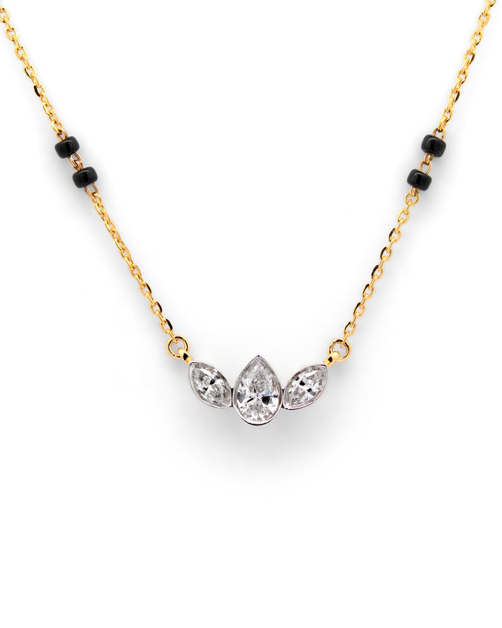 Gold necklace with black beads and three clear gemstones on a white background